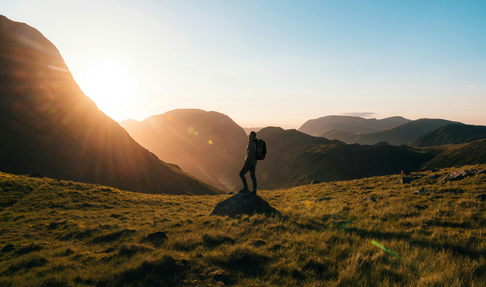 Hiker at sunrise overlooking mountain valley